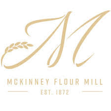 McKinney Flour Mill logo featuring a gold monogram “M,” wheat graphic accents, and establishment year 1872 on a light background.